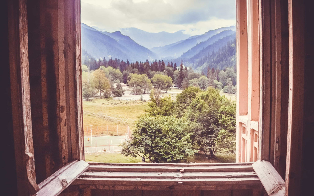 Osiguranje imovine - pogled iz kuće kroz drveni prozor na predivni proplanak